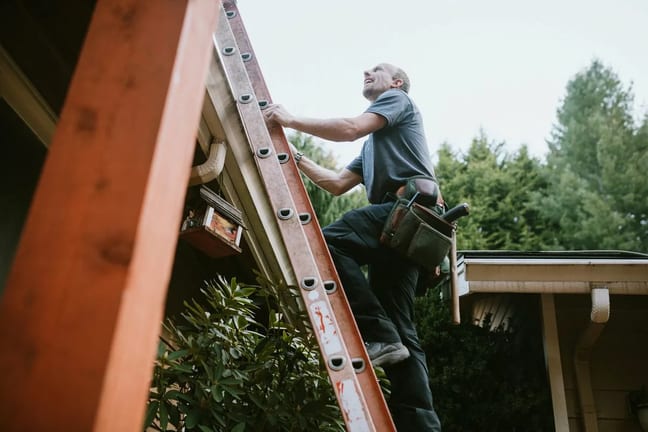 Man with tool belt climbing ladder to roof EJ.width .jpg