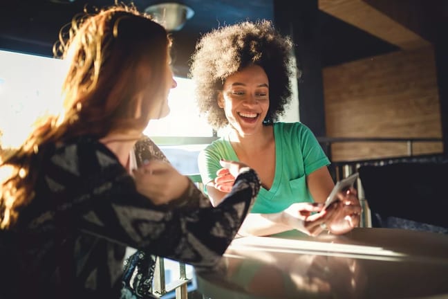 Friends looking at the mobile phone at a cafe.width qMyFab.jpg