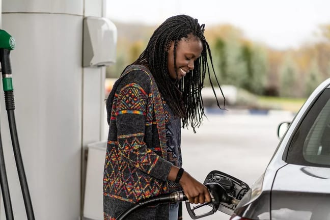 Person smiling while pumping fuel into vehicl.width .jpg