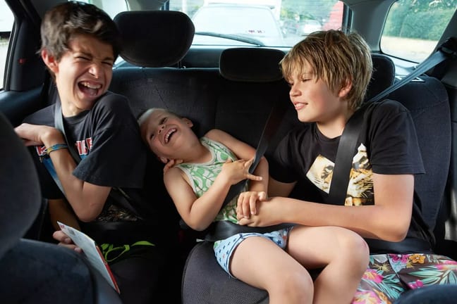 Three children in back seat of car PhNiqCM.width .jpg