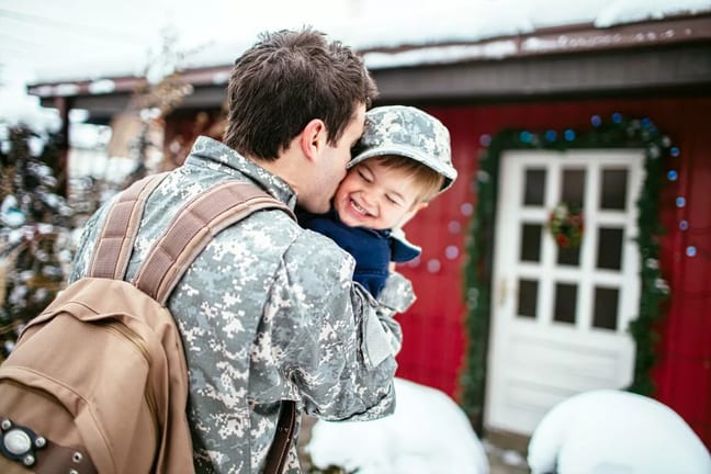 Military father with backpack hugging child o.width CYIFza.jpg