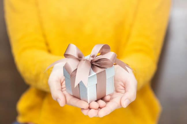 Woman holding small gift BHDbAvx.width .jpg