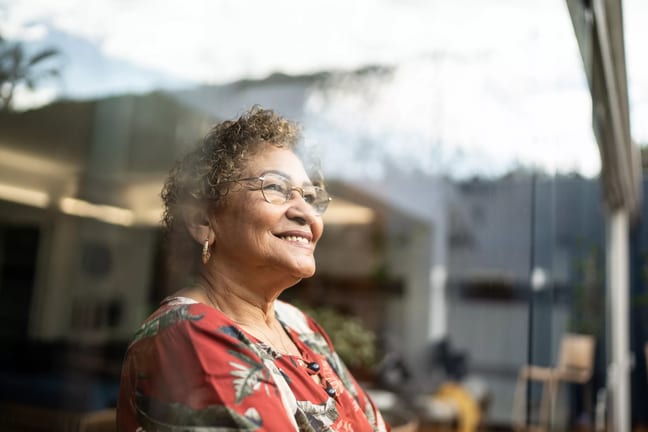older person looking out a window and smiling.jpg
