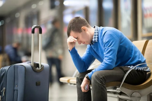 pained young man beside suitcase in airport.width .jpg