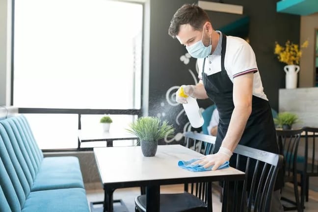 waiter in mask cleaning restaurant table CcOi.width .jpg