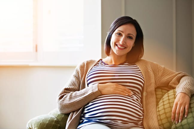 getty pregnant happy smiling on couch.jpg