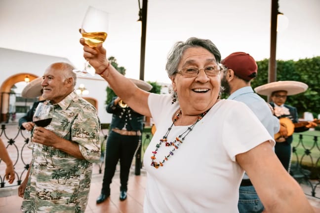 happy senior dancing and raising glass of wine.jpg