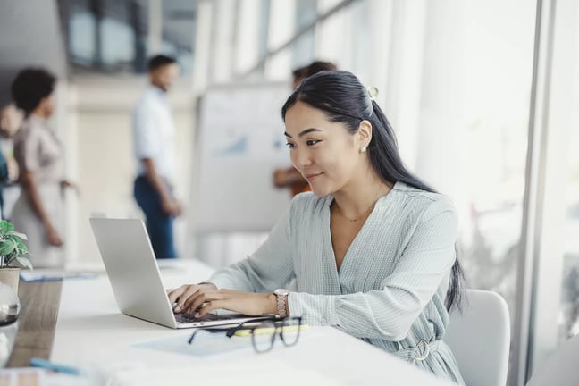young person sitting at a desk in an office looking at a laptop.jpg