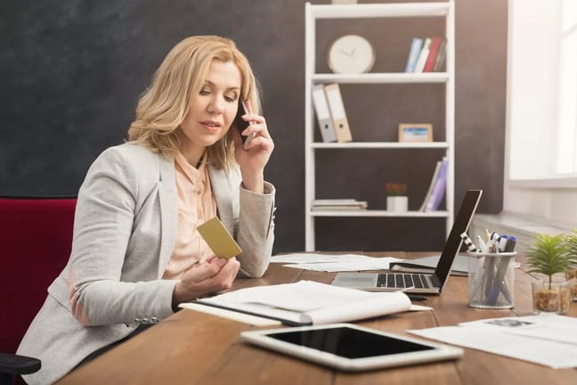 Woman holding credit card while talking on ph.width QhZCHA.jpg