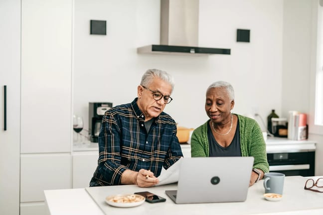 two people sitting in a kitchen looking at a laptop.jpg