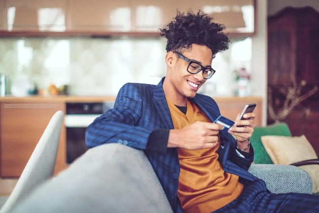 Young man smiles holding credit card XSsJhs.width .jpg