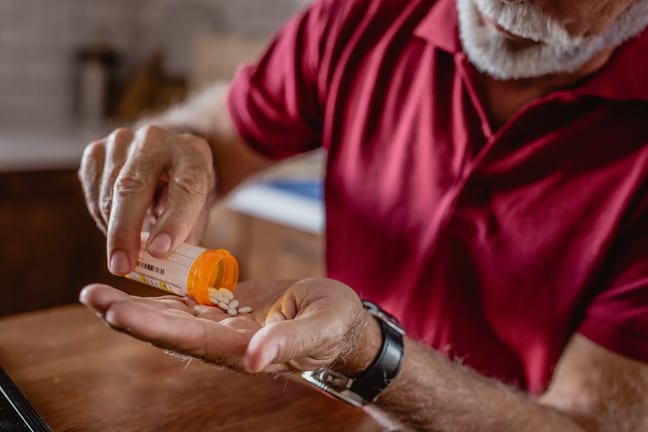 older man pouring pills into hand gettyimages .jpg