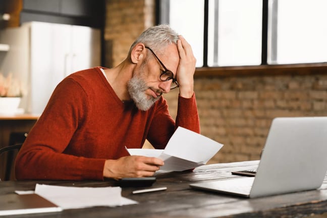 older man stressed holding document at laptop gettyimages .jpg