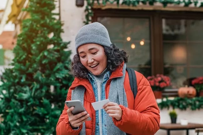 young woman outdoors smiling with phone and c.width zIAeLdf.jpg
