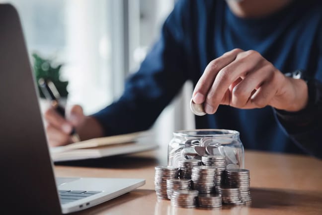 gettyimages saving coins in a jar writing in a journal.jpg