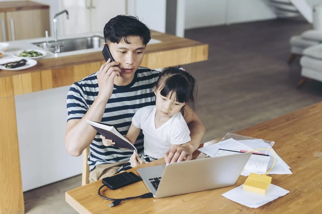 person talking on phone and looking at laptop with child on lap.jpg
