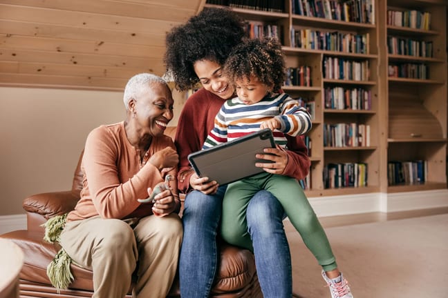 two adults and a child looking at a tablet and smiling.jpg
