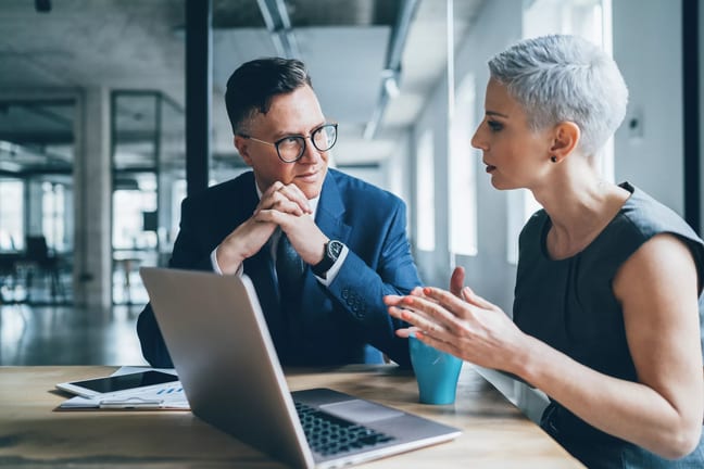 two businesspeople talking in front of a laptop.jpg