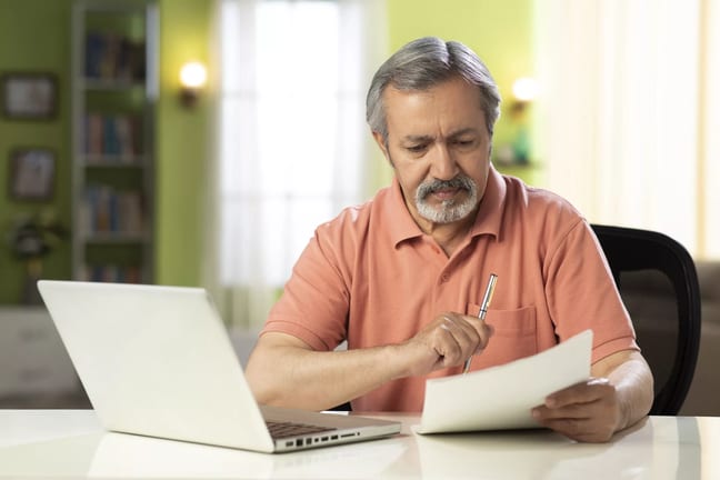 mature person holding pen and looking at document.jpg