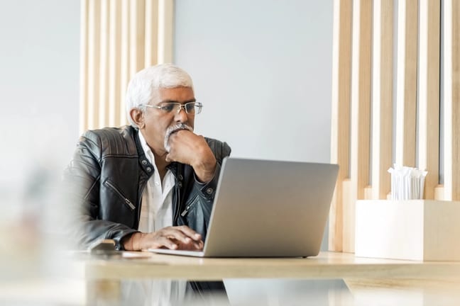 retired older man on laptop working reading news stocks.jpg