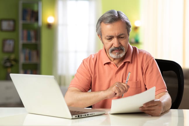 mature person holding pen and looking at document.jpg