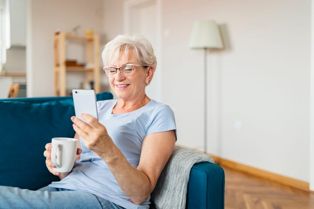 smiling senior holding coffee mug and looking at smartphone.jpg
