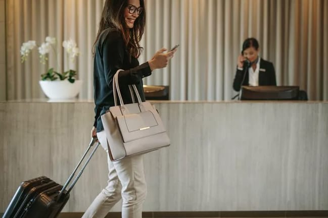 woman with suitcase and phone in hotel lobby.width .jpg