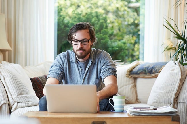 Man sitting on sofa and using laptop at home.width HXjQHwf