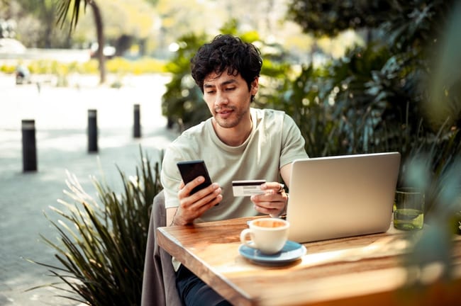 person at outdoor cafe table with laptop phon.width AODczLu.jpg