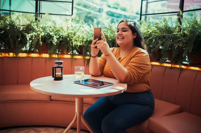 person at coffee shop table with phone JvOTB.width .jpg