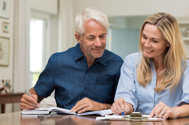 mature couple discussing finances with pens and paper
