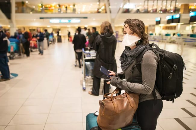 Masked woman with luggage waiting in an airpo.width ogAmB.jpg
