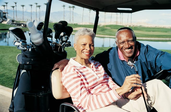 senior man and woman sitting in golf cart smiling poc.jpg