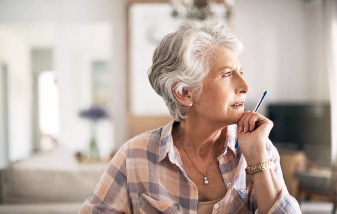 older person looking thoughtful while holding a pen.jpg