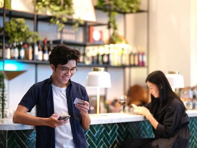 man in restaurant holding phone and credit ca.width UCoaDCF.jpg