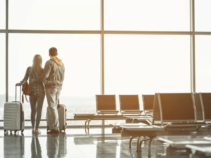 couple with suitcases at airport window.width .jpg