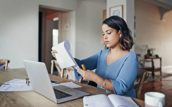 woman with bills and laptop in kitchen.width .jpg