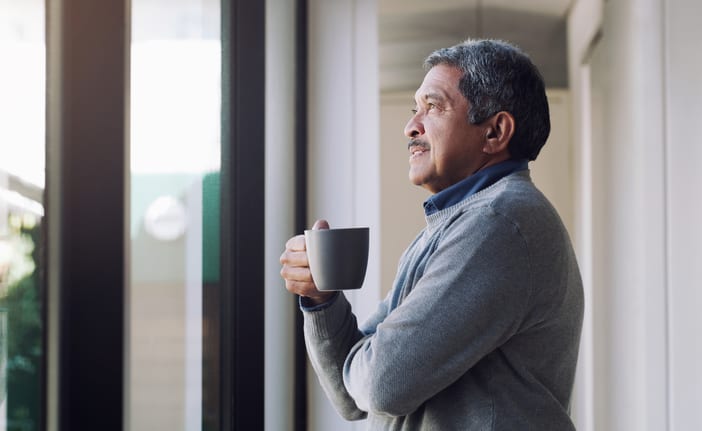 older person holding a mug and looking out a window ifSeK7