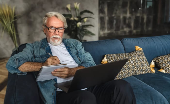 senior holding laptop and writing note in notebook.jpg