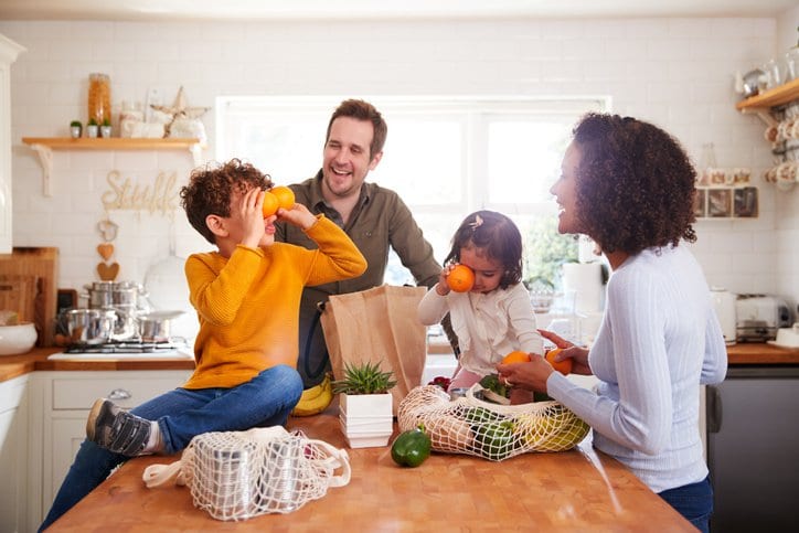 family unpacking groceries in kitchen.width