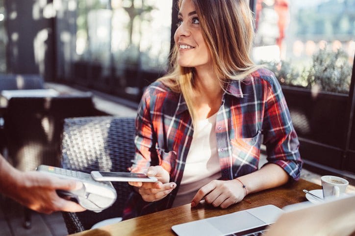 woman in restaurant paying with smart phone a.width