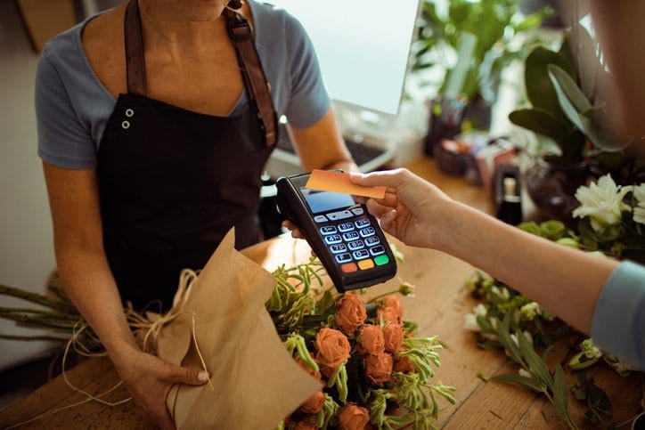 woman holding credit card over payment reader.width IAlpwc.jpg