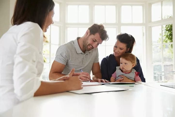 couple with baby signing house closing docume.width .jpg