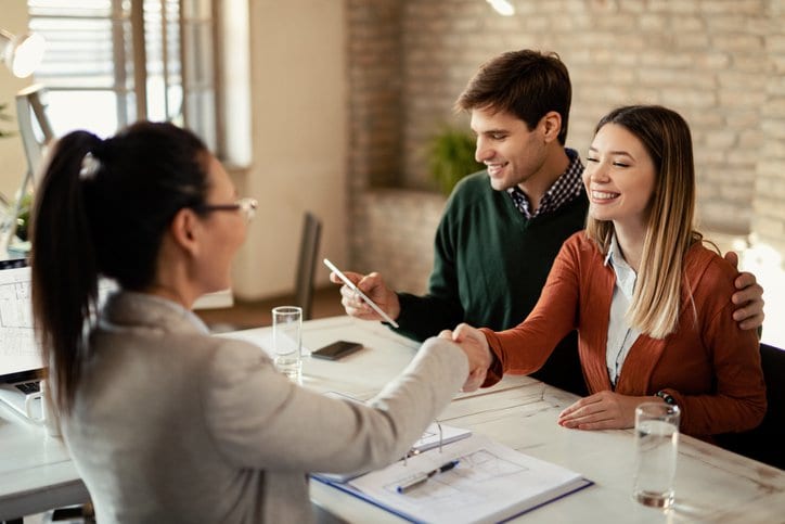 couple signing mortgage and shaking hands wit.width .jpg