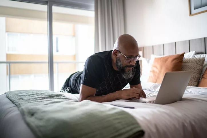 person lying on bed using laptop zxzVvg.width .jpg