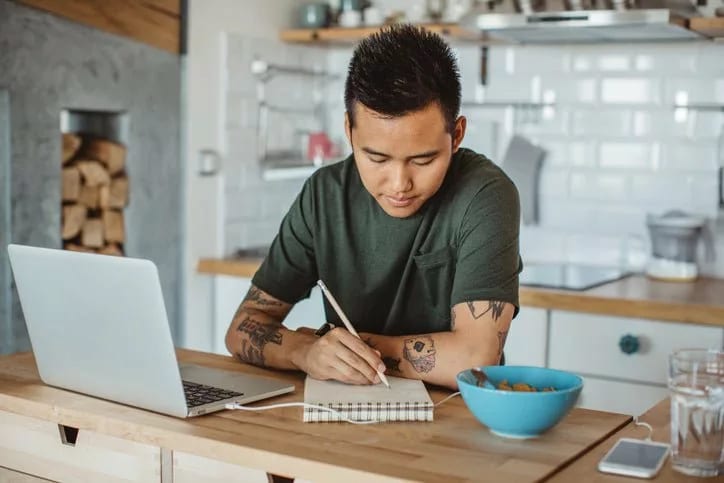 man at table writing in notebook NHASUaV.width .jpg