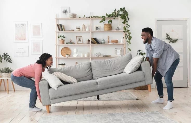 man and woman moving couch in living room MHH.width .jpg