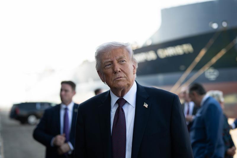 Donald Trump is preparing to deliver remarks, flanked by several government officials.