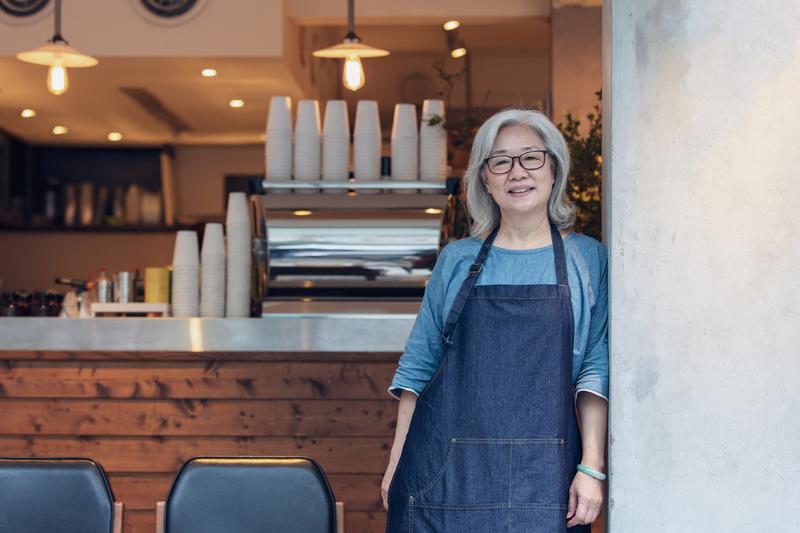 Smiling person in apron in cafe.