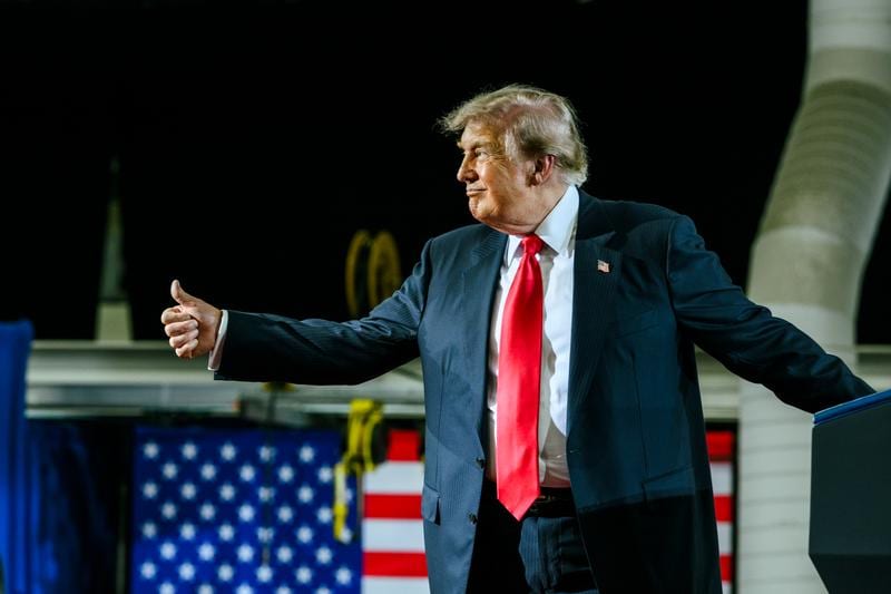 Donald Trump is giving a thumbs-up to the crowd while on stage.